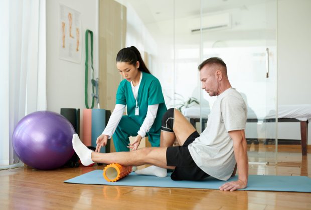 Patient Doing Myofascial Release Rehabilitation specialist teaching patient how to do myofascial release for legs